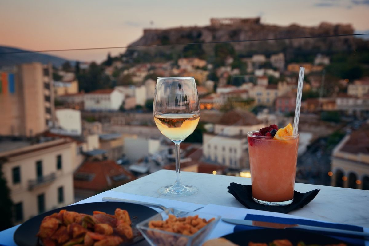 Rooftop drinks and small bites in Athens, with the Acropolis blurred in the background.